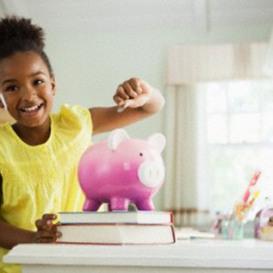 Girl putting money into piggy bank
