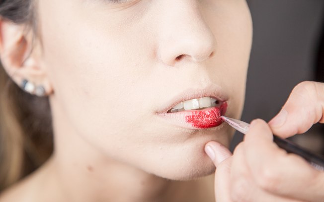 Cubra os lábios com batom vermelho bem vibrante. Use pincel para mais definição